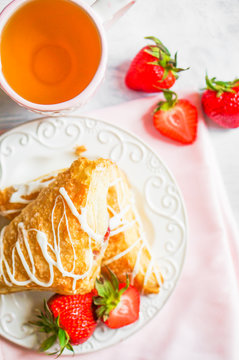 Fresh croissants with strawberries on wooden background