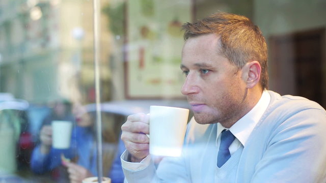 Pensive businessman drinking coffee in the cafe, steadycam shot.