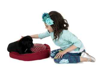girl kneeling down petter her black lab puppy