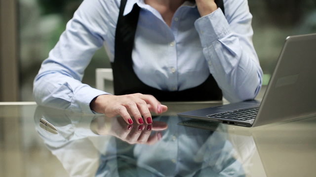 Businesswoman fingers taping on glass desk in office.