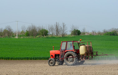 Obraz premium Tractor sprinkling pesticides againt bugs
