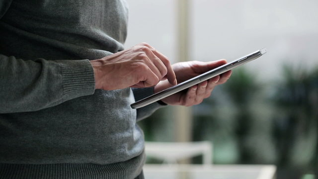 Man touching screen and browsing on tablet, closeup