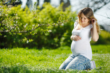 Fototapeta na wymiar Portrait Healthy pregnant woman sitting on green grass