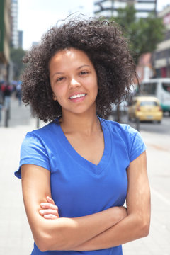 Attractive woman with curly hair and crossed arms in the city