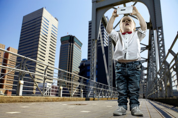 Boy with gadget on the bridge in the city of skyscrapers