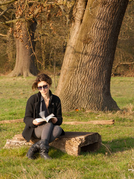 A woman is reading sitting under a tree