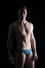 Fototapeta na wymiar Chiaroscuro photo of shirtless young man standing