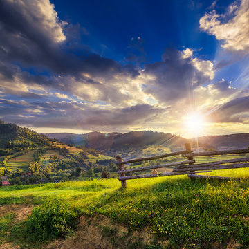 wooden fence in the grass on the hillside at sunset