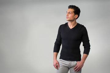 Handsome latin young man standing on grey background.