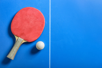 Pin pong ball with red paddle on blue board