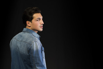 Young man w denim shirt seen from the back, looking to a side