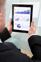 Businessman looking at graphs on his tablet