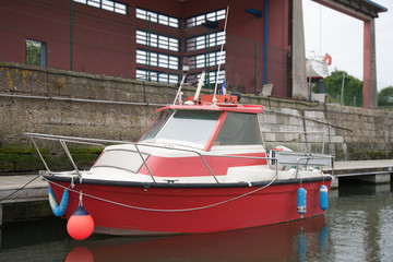 Fototapeta na wymiar Floating small red motorboat at the dock