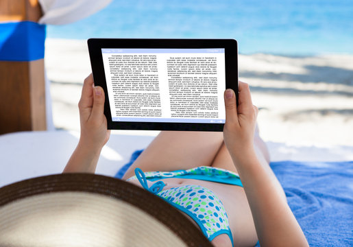 Woman Reading E-Book At Beach