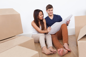 Couple Looking At Blueprint In New Home