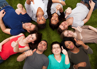 College Students Gesturing Thumbs Up While Lying On Grass