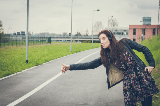 Pretty girl with long hair hitchhiking in the street