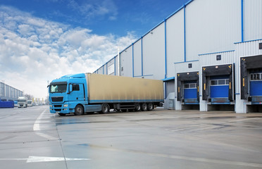 Unloading cargo truck at warehouse building - obrazy, fototapety, plakaty