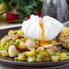 Hot salad with potatoes, ham, peas, mushrooms, poached egg