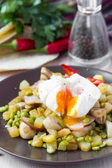 Hot salad with potatoes, ham, peas, mushrooms, poached egg