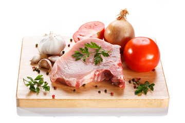 Raw pork on cutting board and vegetables