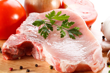 Raw pork on cutting board and vegetables