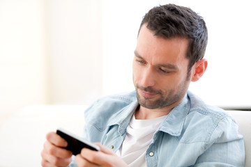 Young relaxed man sending text in a sofa