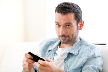 Young relaxed man sending text in a sofa