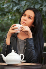 Young woman drinking tea at sidewalk cafe