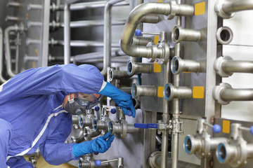 Technician in overalls maintaining technological system in plant