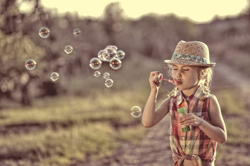 carefree girl lets soap bubbles on a warm day