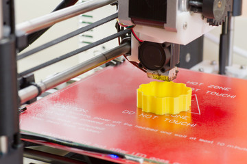 Three dimensional printer in action, printing an object from yellow ABS filament