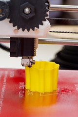 Close up view of a three dimensional printer creating a yellow object, 3D printer detail