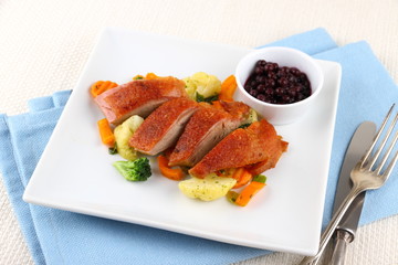 Roasted duck breast with vegetables and cutlery
