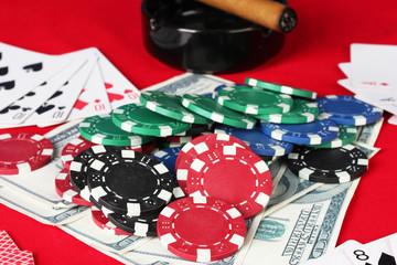 The red poker table with playing cards, poker chips and dollars