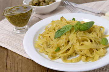 Delicious pasta with pesto on plate on table close-up