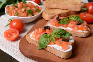 Delicious bruschetta with tomatoes on cutting board close-up
