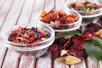 Aromatic dry tea in bowls on wooden background