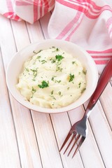 Delicious mashed potatoes with greens in bowl on table close-up