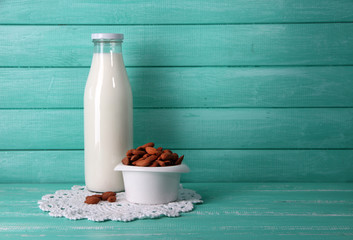 Almond milk in bottle with almonds in bowl,