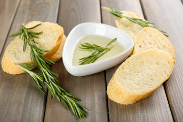 Fresh bread with olive oil and rosemary on wooden table