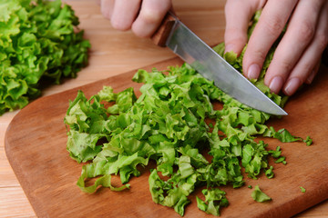 Chopped green lettuce on wooden board close-up