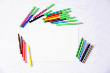 Fototapeta premium Colored pencils and blank paper sheet on wooden table