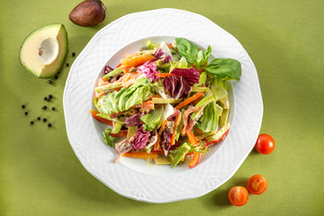 salad with avocado and cherry tomatoes on green background, top