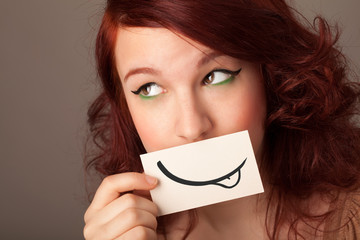 Pretty young girl holding white card with smile drawing