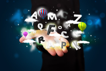 Young businessman presenting magical clouds with letters and bal