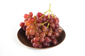 Red grapes in a dish on white background.