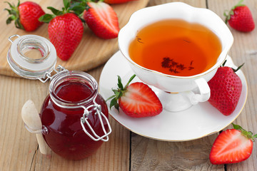 Fresh strawberry jam in glass jar with rooibos tea in white cup