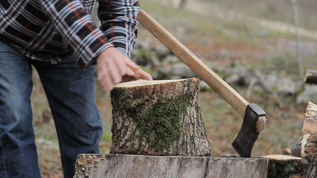 Man with an ax chops wood for heating