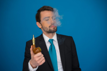 businessman with e-cigarette wearing suit and tie on blue